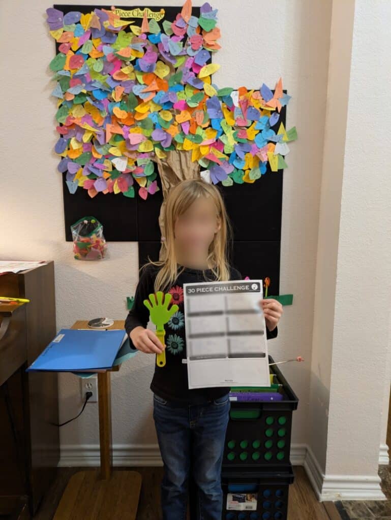Image of a smiling child holding an award in front of the studio decoration and incentive tree.